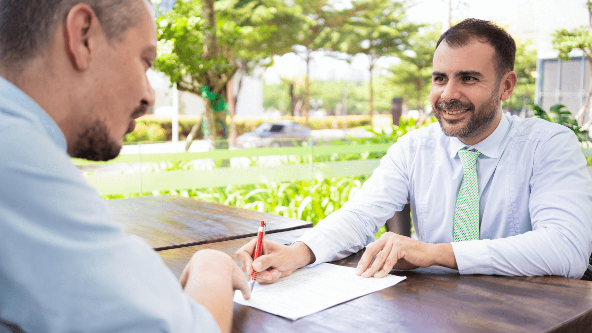 Pessoas assinando contrato ao ar livre